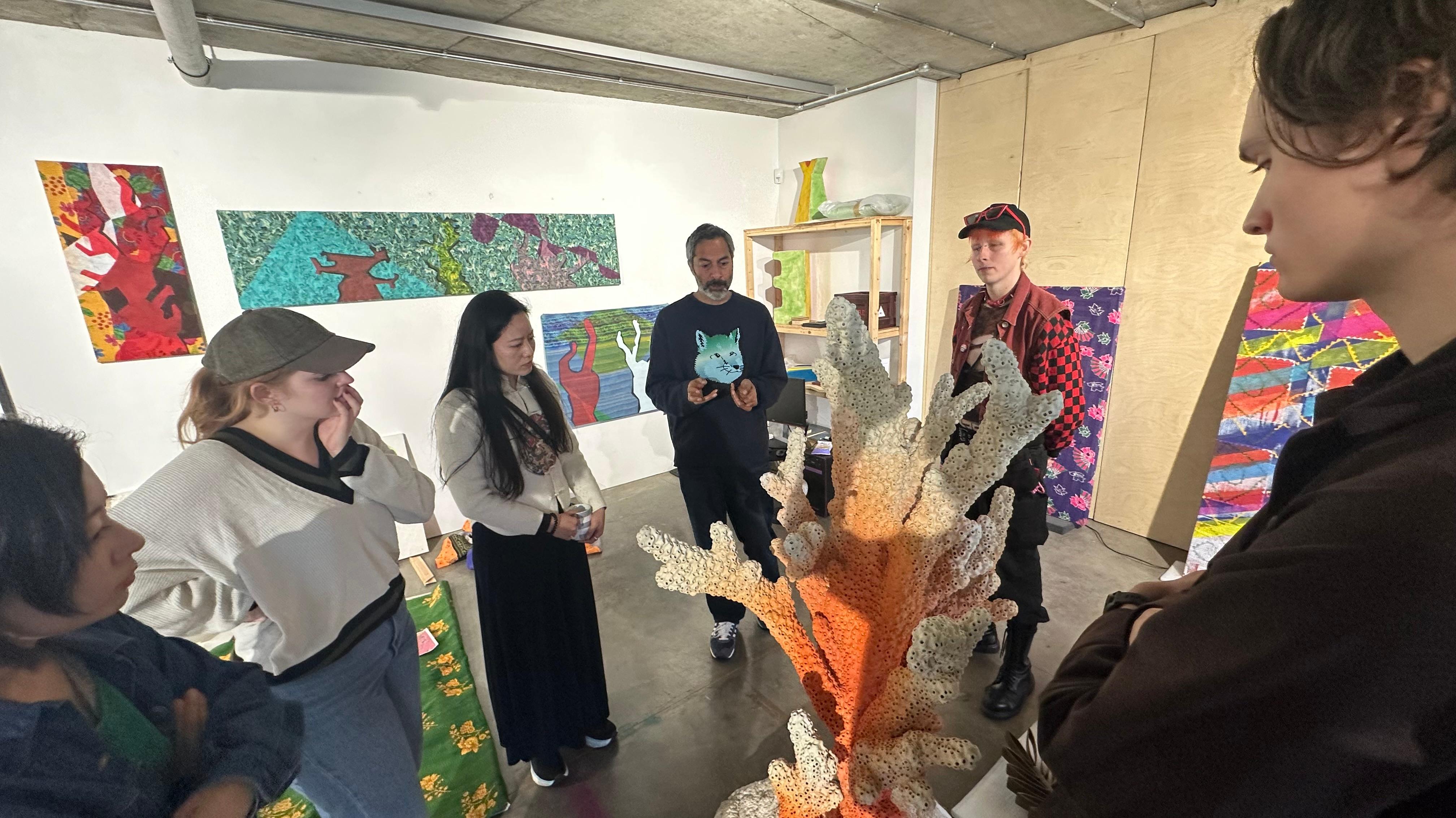 Students and their tutor viewing a sculptural object in a studio setting.