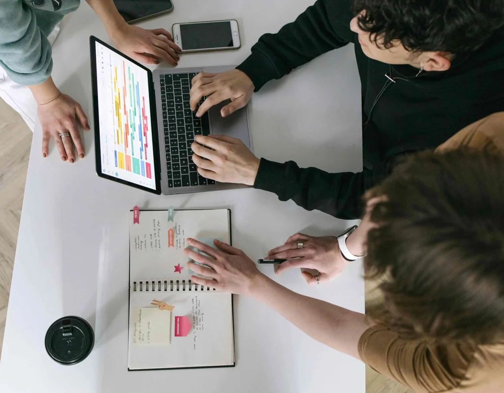 People discussing project plan displayed on a laptop screen