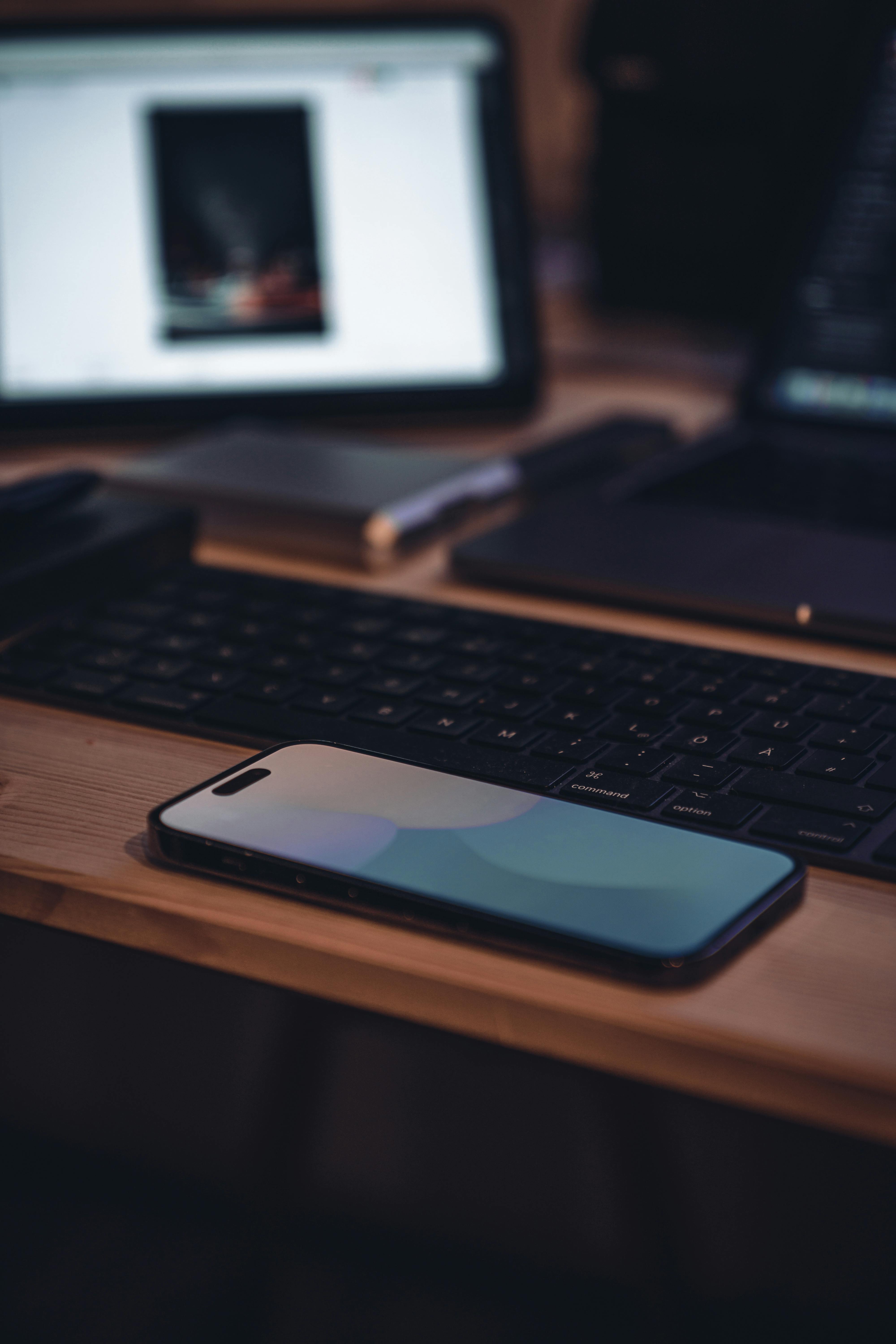 Laptop and tablet on a desk, next to a book and a plant
