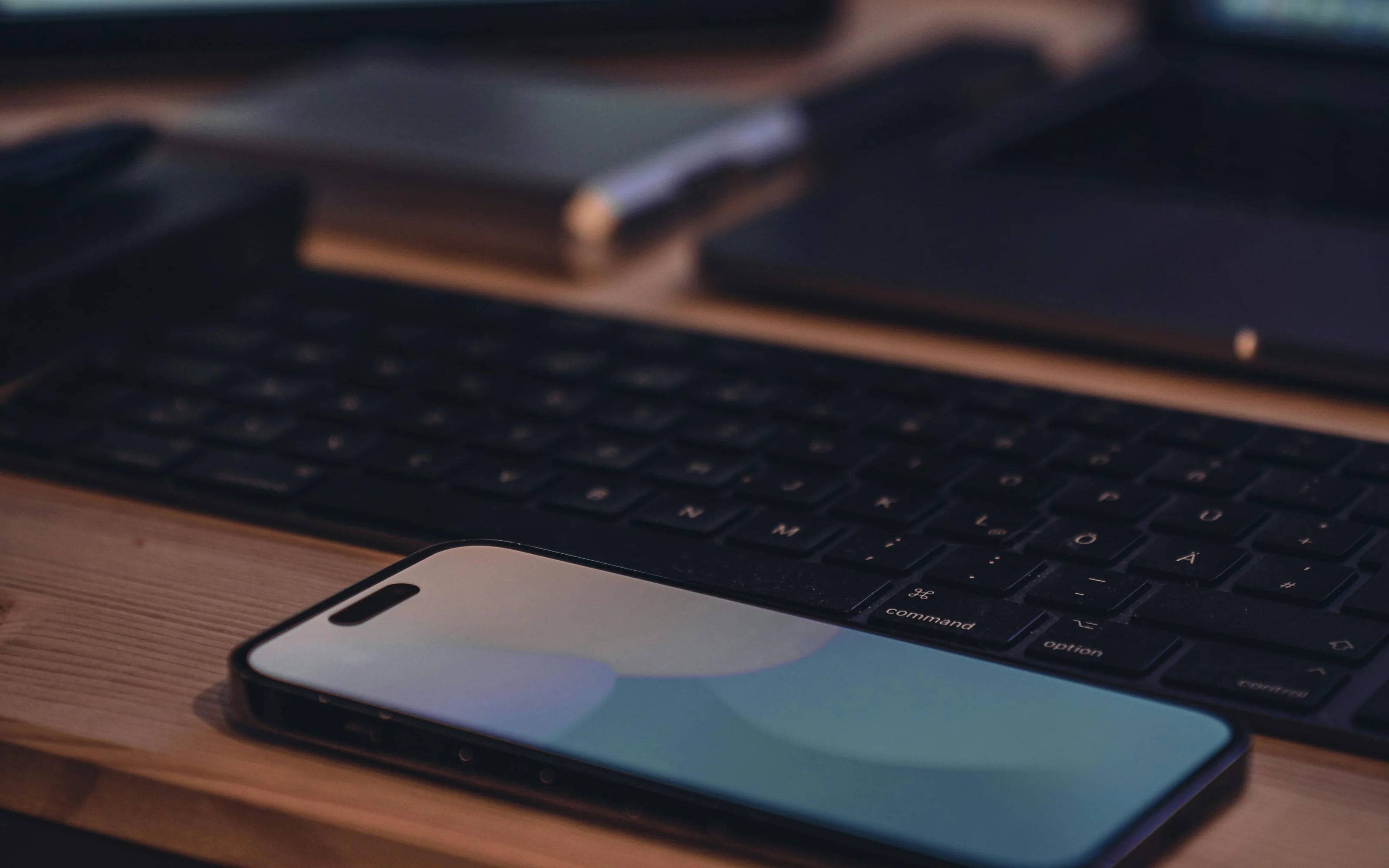 Laptop and tablet on a desk, next to a book and a plant