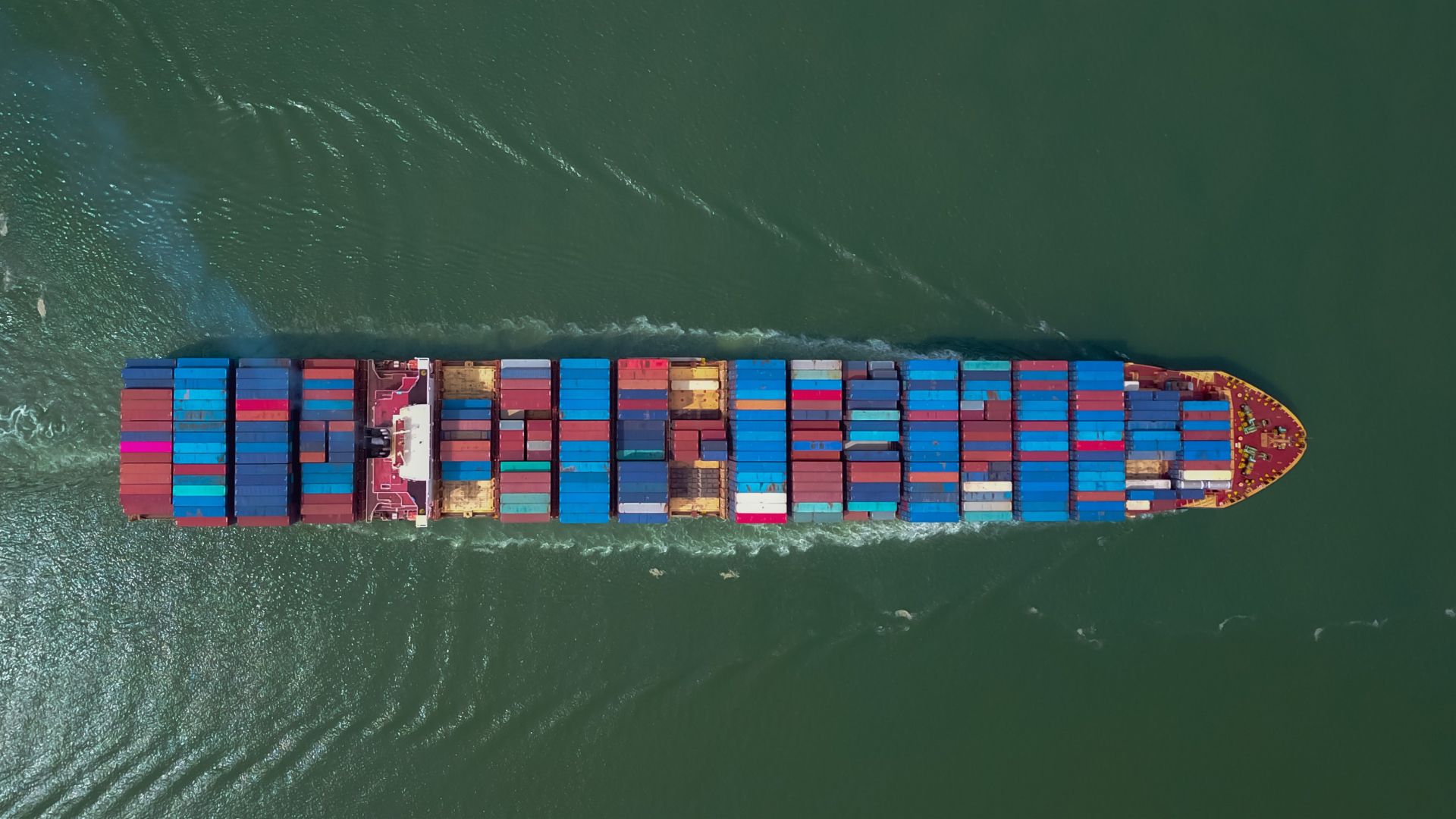 Overhead view of cargo ship piled with containers in transit. 