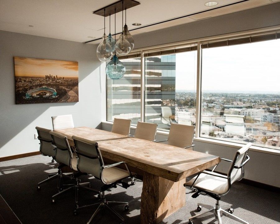 Corporate boardroom with desk and chairs and a view of a city out the window.