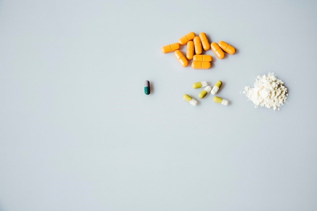 Minimalist image of pills and powders against a grey background. 