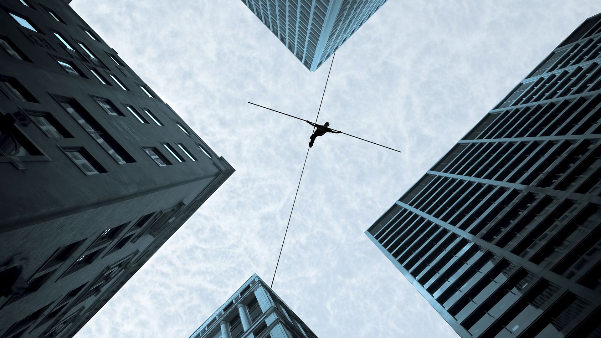 A person walking a tightrope between office buildings