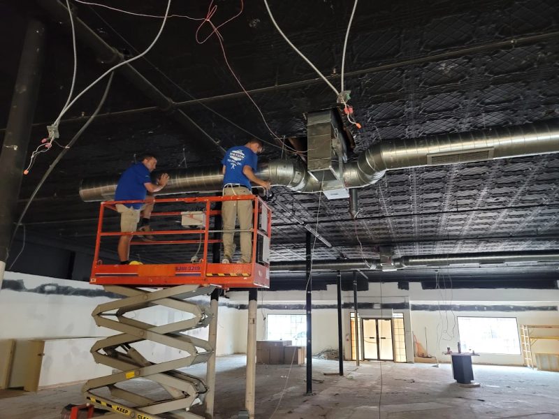 Two Watson technicians on a scissor lift installing commercial ductwork