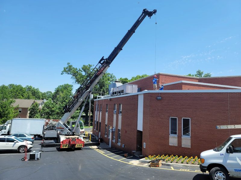 Rooftop HVAC unit being lifted by crane during a commercial replacement