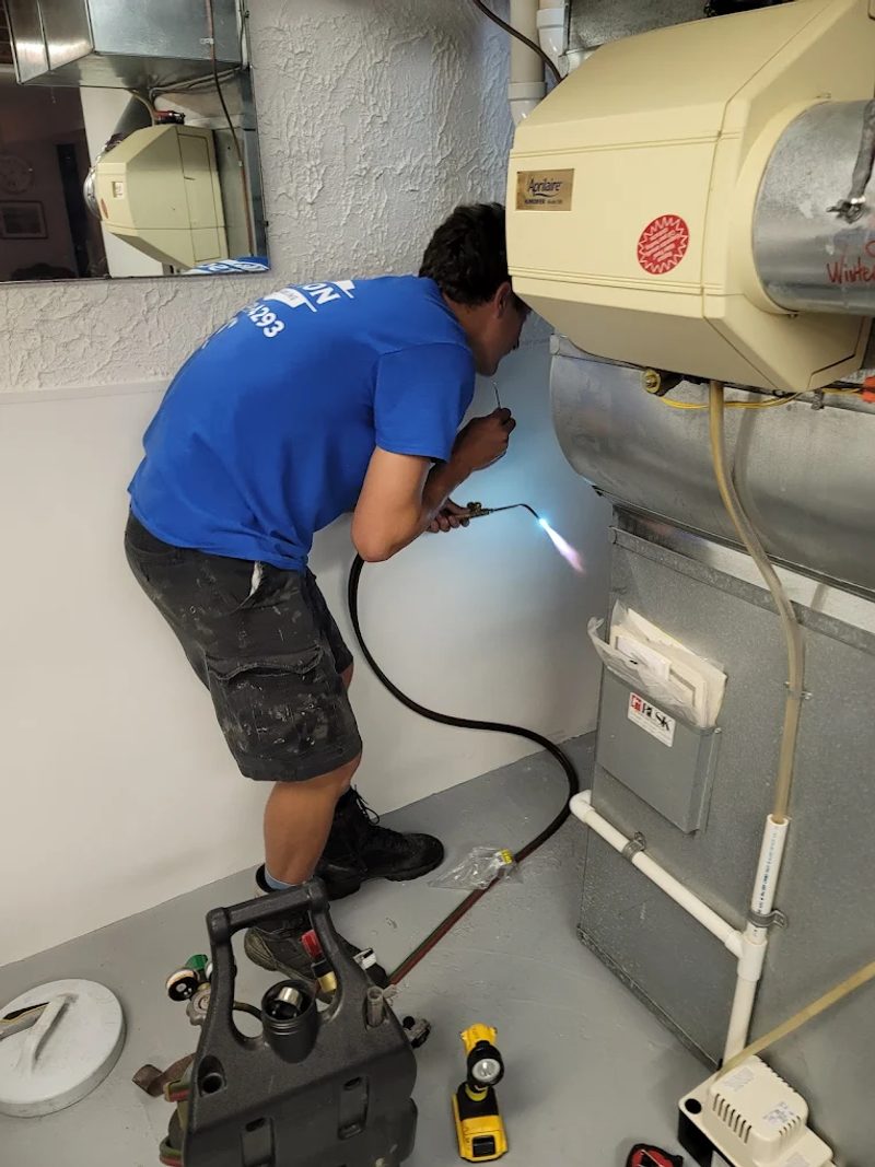Watson Heating + Cooling technician brazing a refrigerant line during a furnace install