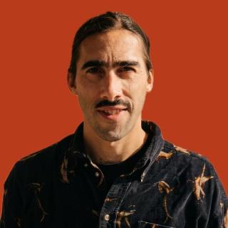 Nicolas Florin, in a patterned dark shirt against a rust background.