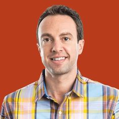 Aaron Goldman, smiling, in a plaid shirt against a rust background.
