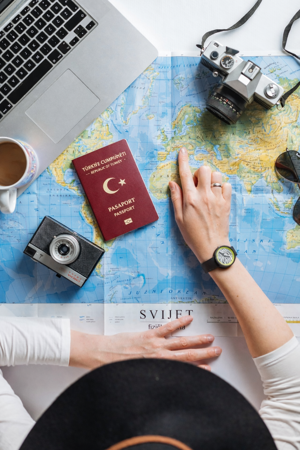 masa üzerinde pasaport, fotoğraf makinası, laptop ve harita