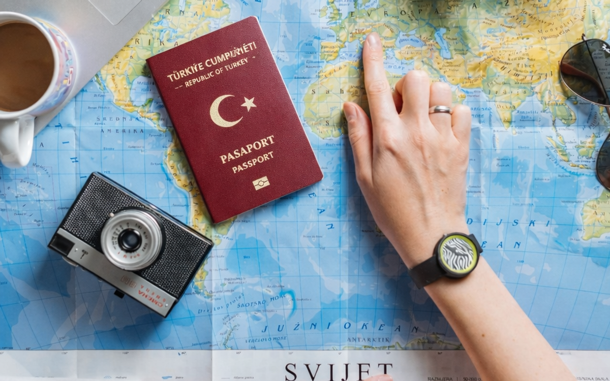 masa üzerinde pasaport, fotoğraf makinası, laptop ve harita