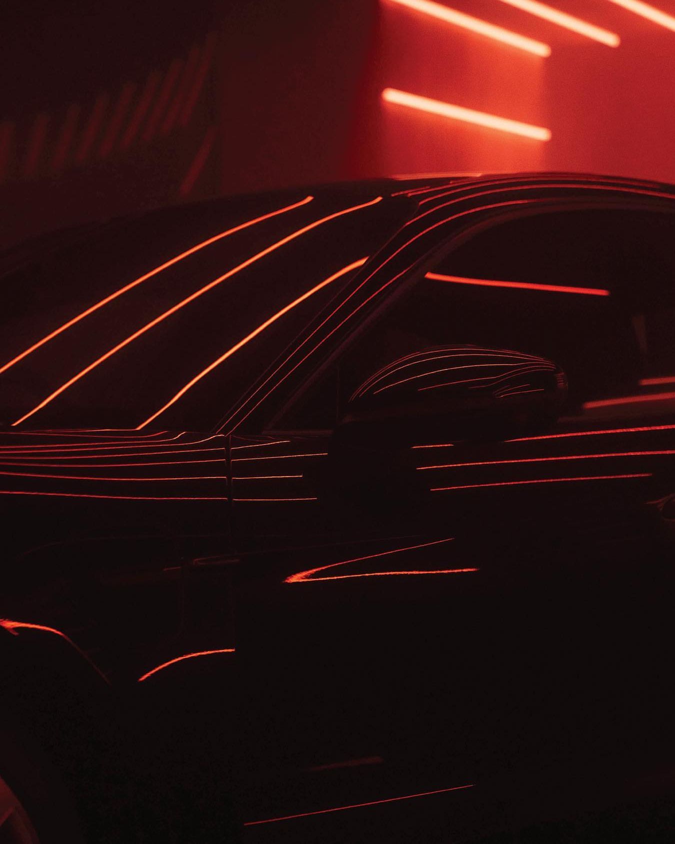 Close up of the Taycan with horizontal red lights illuminating the room. 