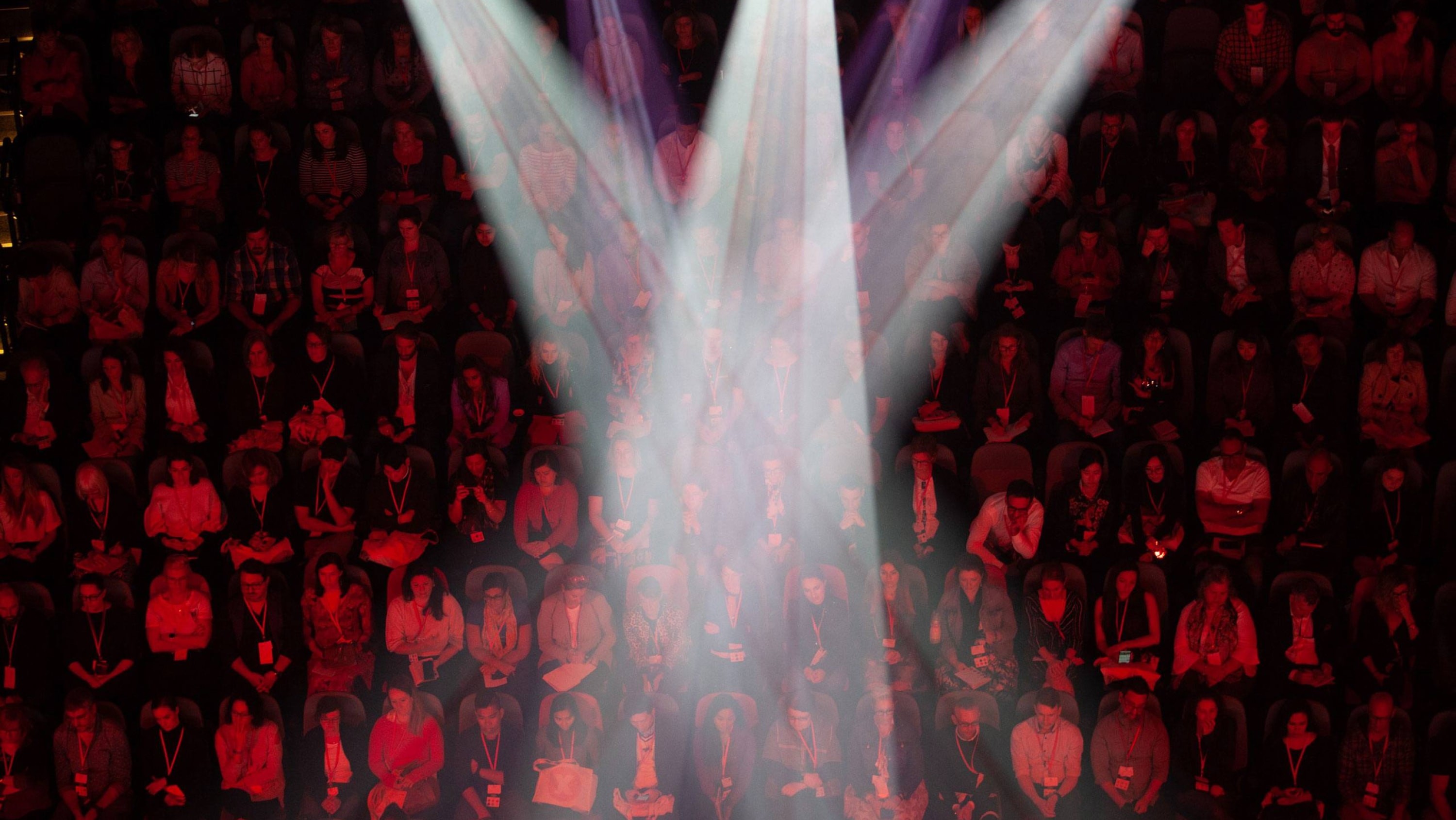 A top down view of stage lights shining down on the audience of the event.