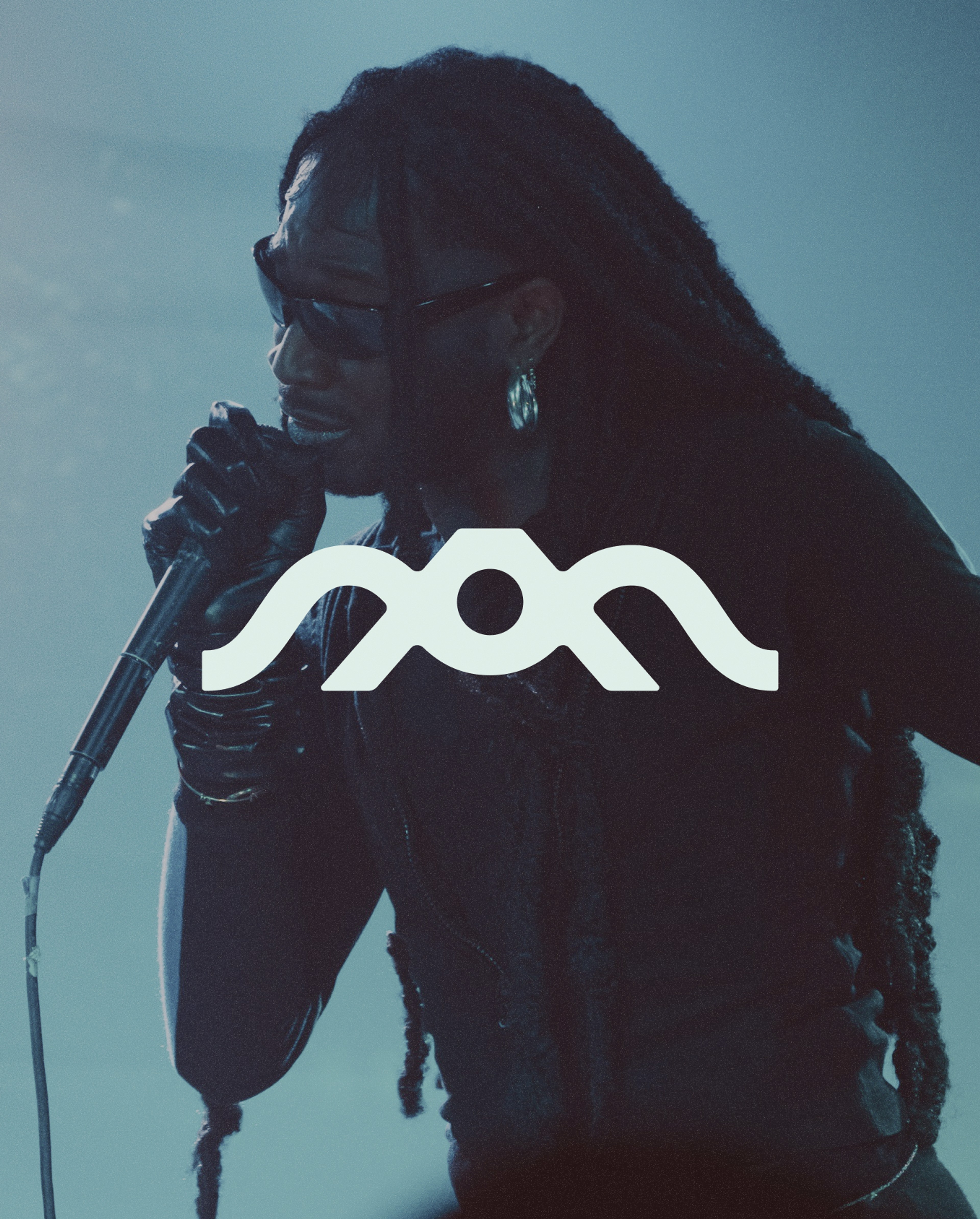 Australian Music Touring Network (AMTN) symbol over a singer performing under blue lighting.