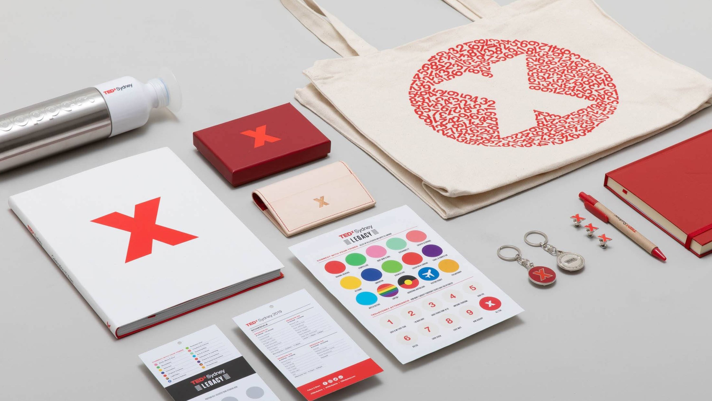 A close up crop of stationary and event collateral with the logo, logomark and central event graphic primarily showcased across the items. 