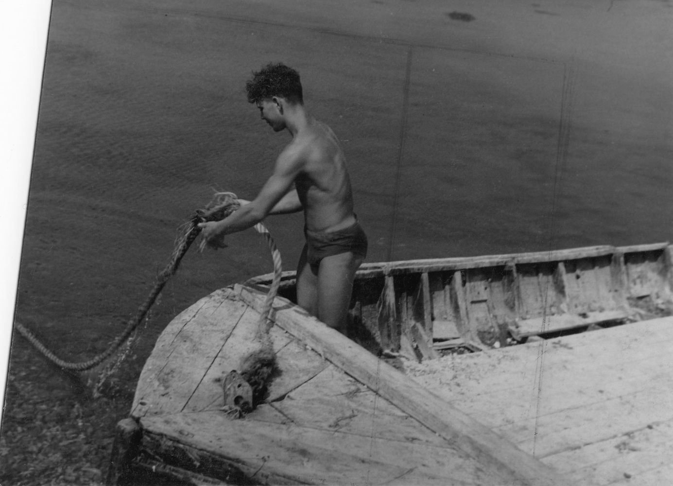 Male figure in boat pulling on rope [P25]