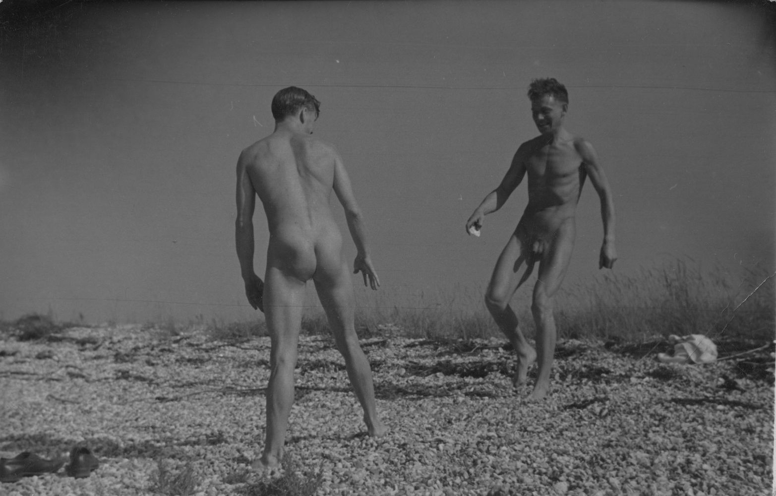 Two naked men facing each other on beach [P30]