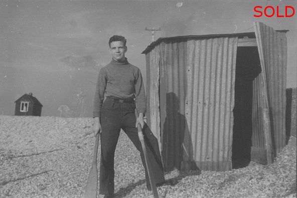 A Young Man beside a corrugated shed, holding oars [P28]