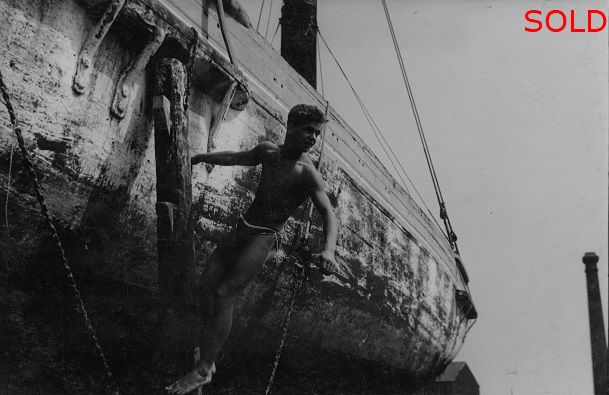 Male figure hanging off wooden dock joist [P56]