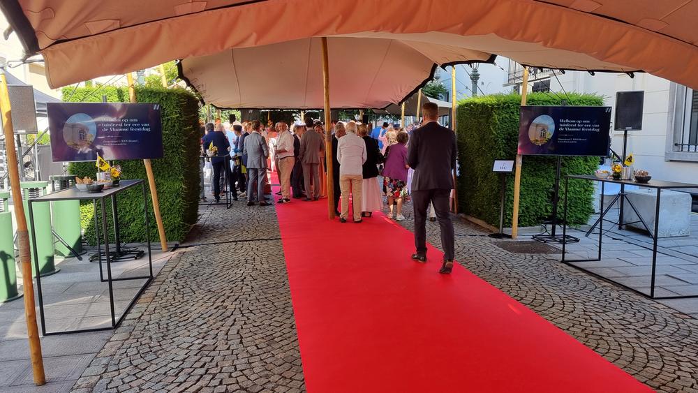 Red carpet entrance under a tent with welcome screens for De Warande's Flemish holiday reception