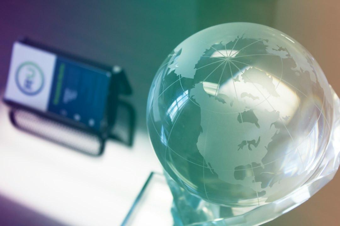 Glass globe paperweight on a desk, with a blurred business card holder in the background