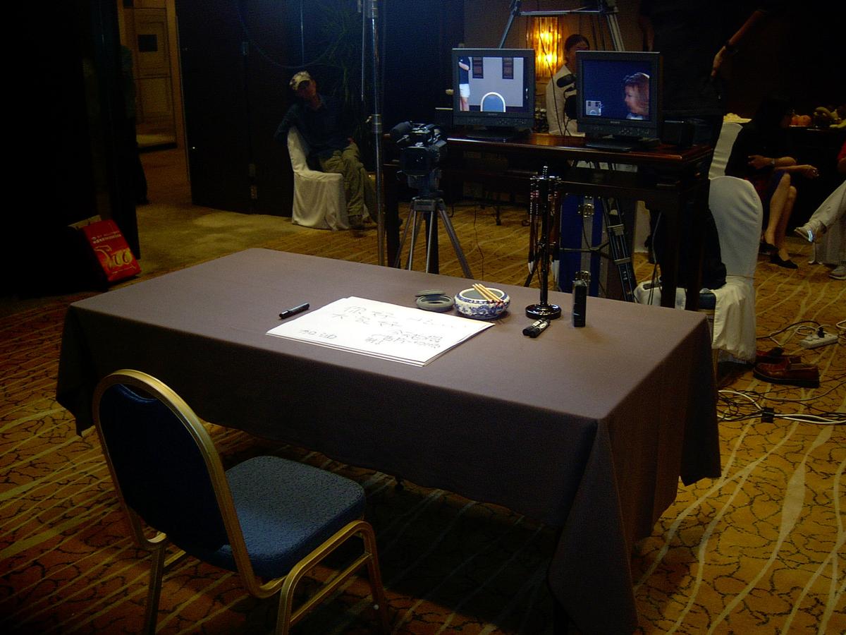 Empty calligraphy table with brushes, ink and paper, facing a camera and two preview monitors