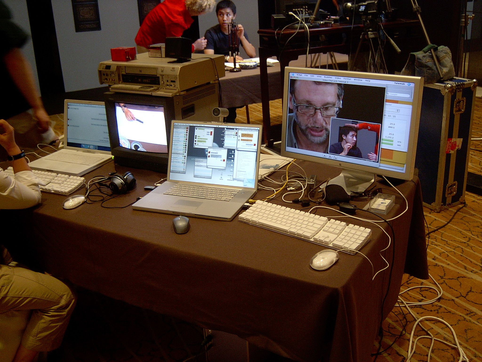 Telemak streaming setup in a hotel function room: laptops, a CRT monitor and a screen showing a video call