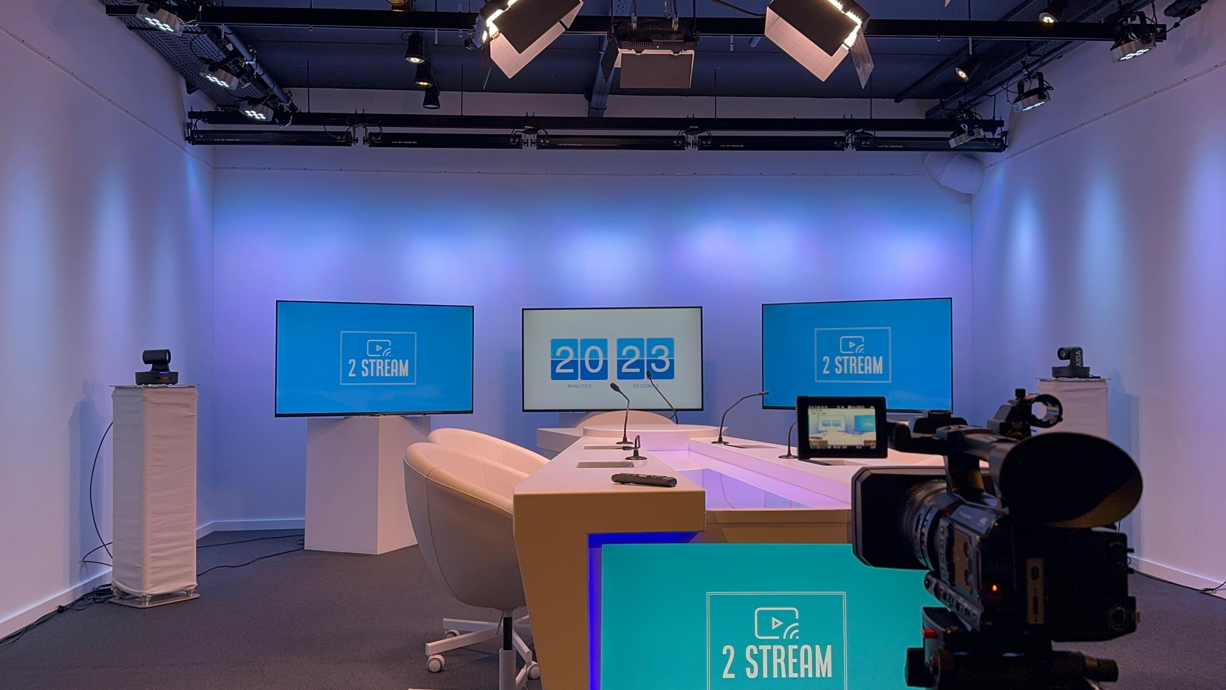 The 2 Stream studio in Zaventem: a lit desk, three screens and a camera, ready to record