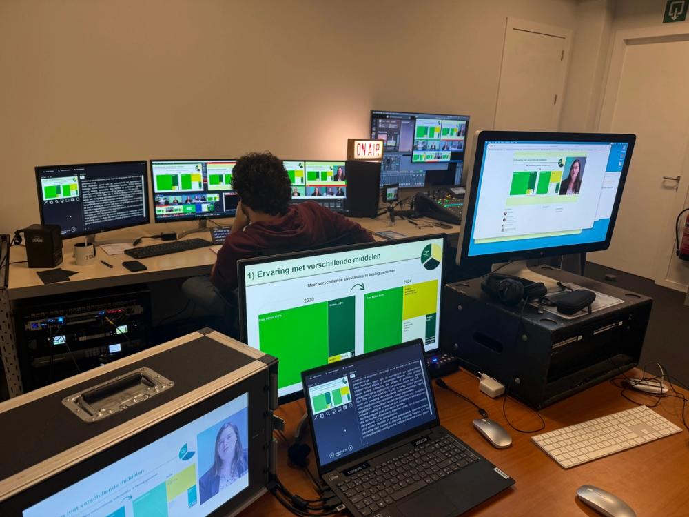 Operator at a control desk with an ON AIR sign, producing a Sciensano webinar with Dutch charts on the screens