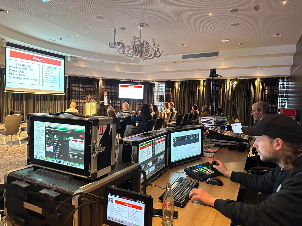 A live production desk with vision mixer and multiviewer screens at the back of an event room