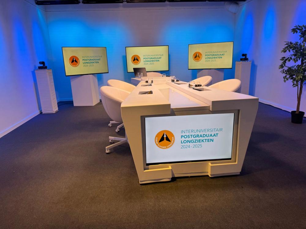 Studio set for the Interuniversitair Postgraduaat Longziekten: a white desk, four chairs and branded screens