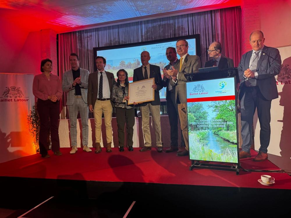 Laureates holding a framed certificate on stage at the Baillet Latour Prijs voor het Leefmilieu 2025 in Lummen