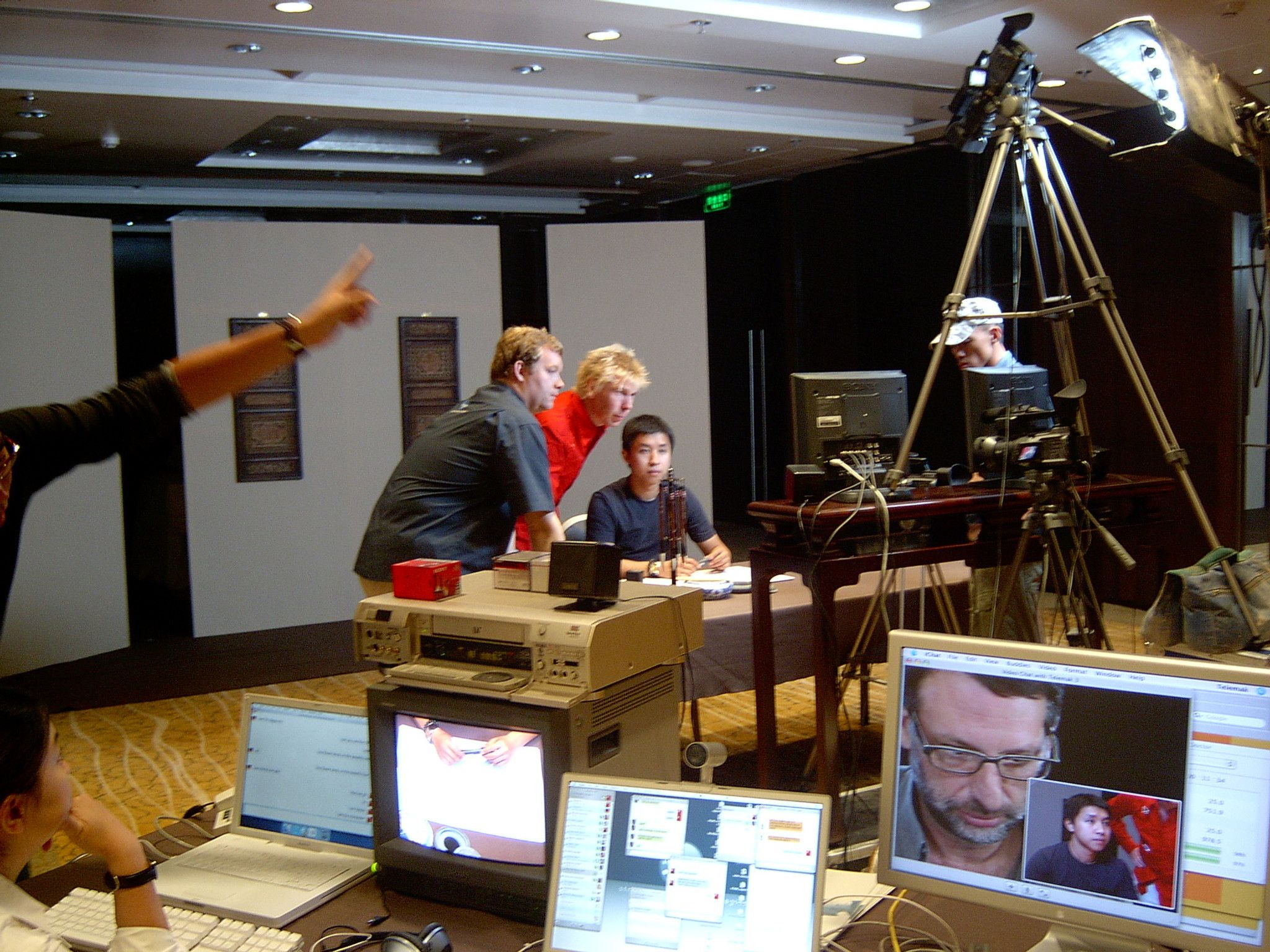 Telemak crew preparing a live stream in a hotel meeting room, with a tripod camera and a video call on a monitor