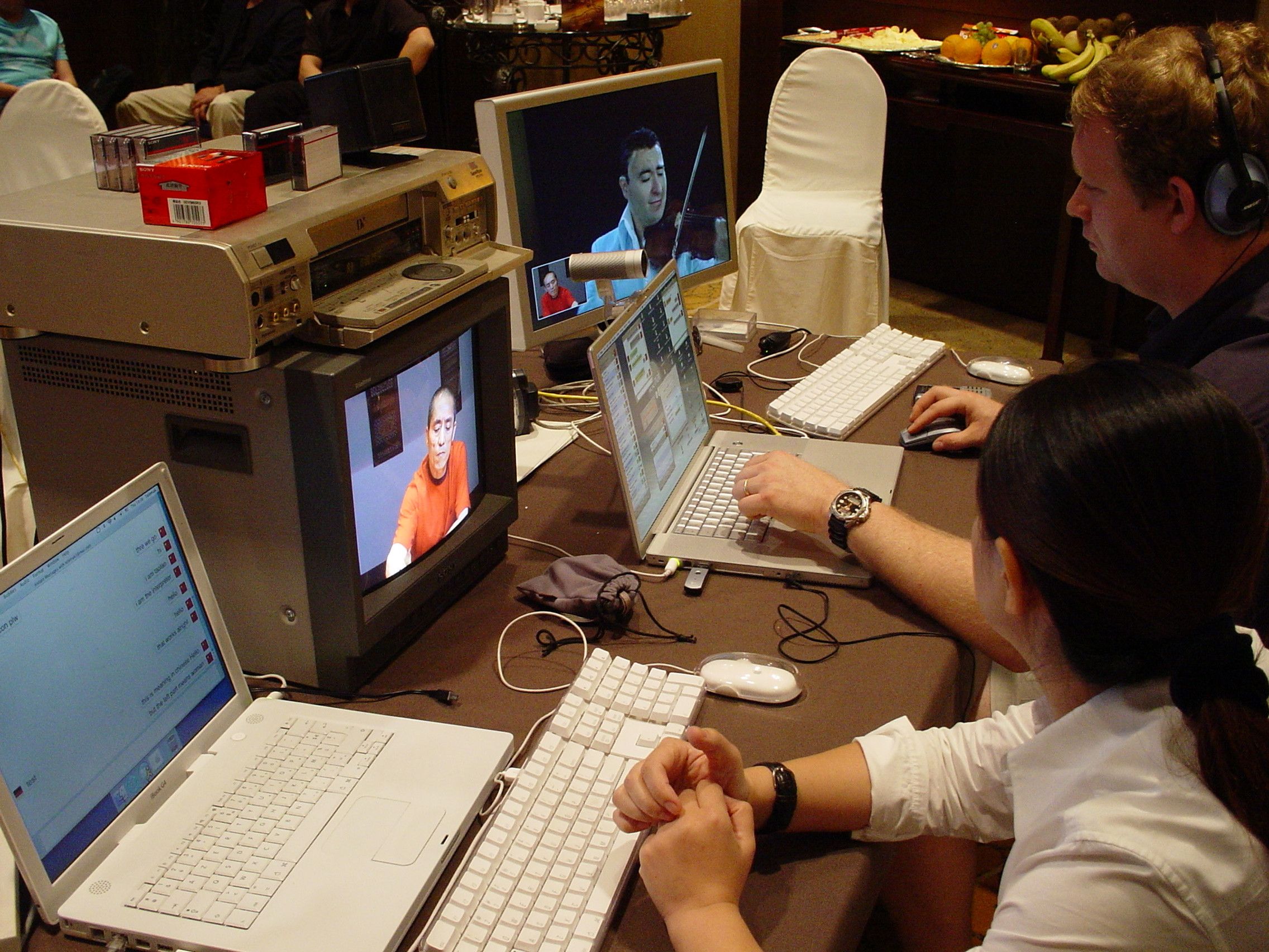 Operators at laptops and monitors showing live feeds of a violinist and a man in red during the stream