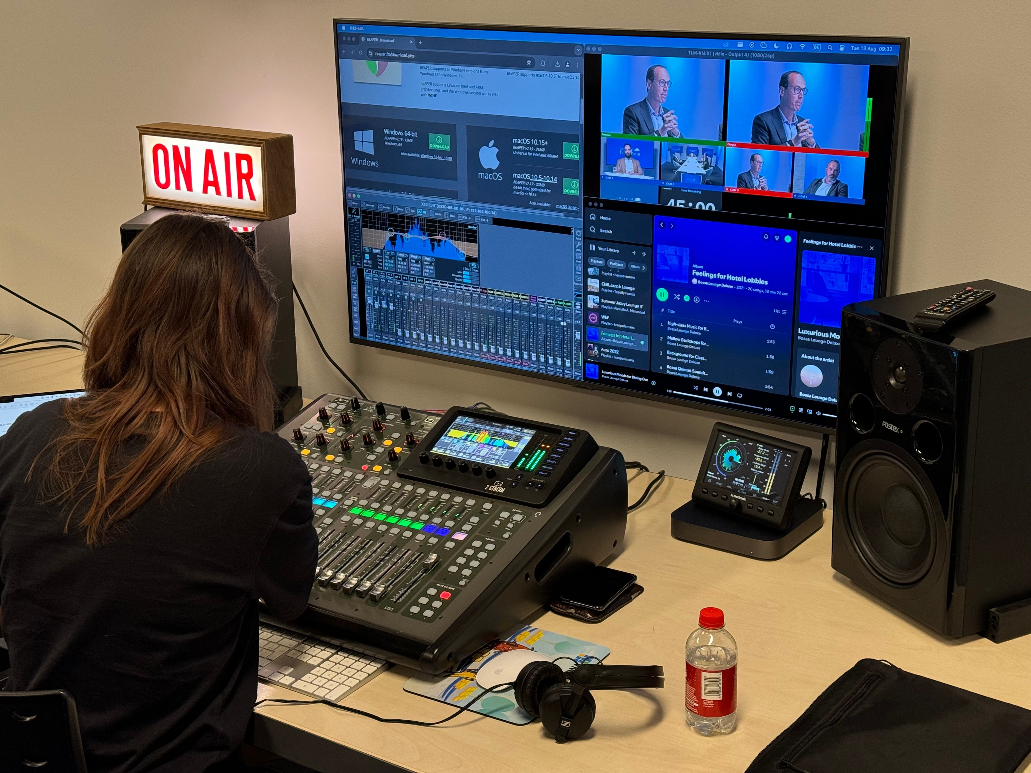 A podcast being recorded: an audio desk and editing screens under a lit ON AIR sign