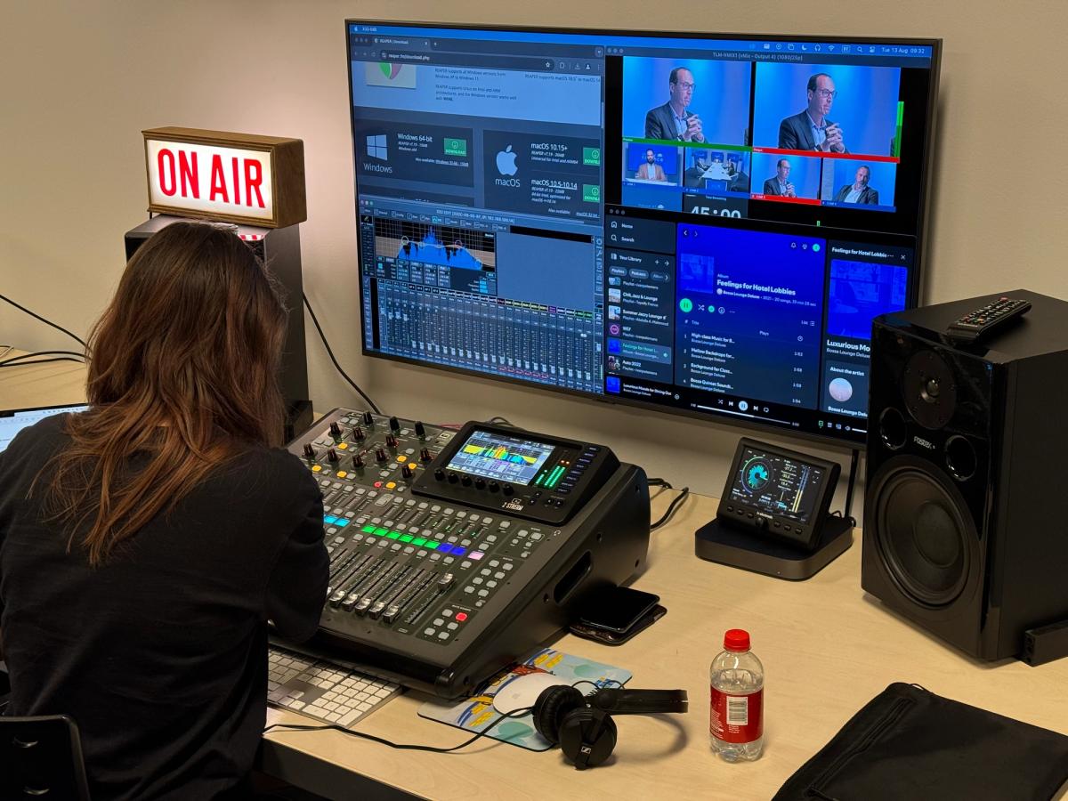 A podcast being recorded: an audio desk and editing screens under a lit ON AIR sign