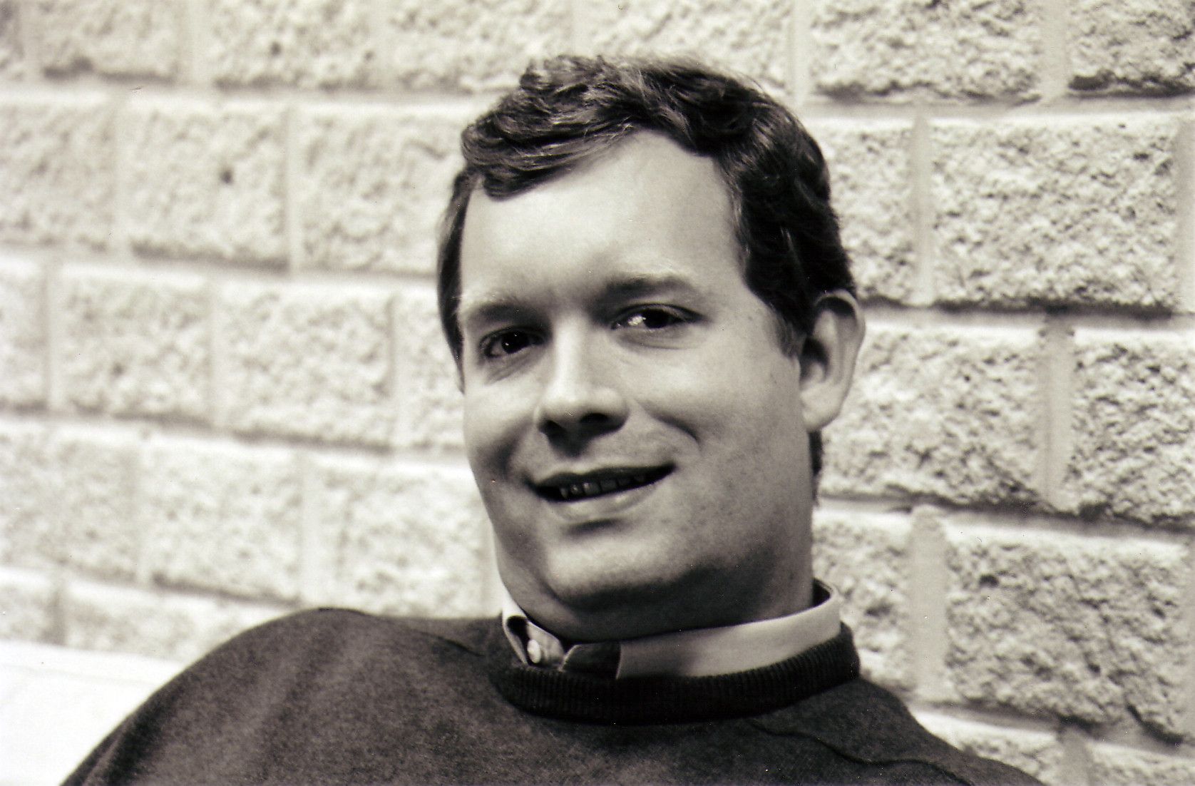 Black-and-white portrait of a young Christophe Lenaerts smiling in front of a brick wall
