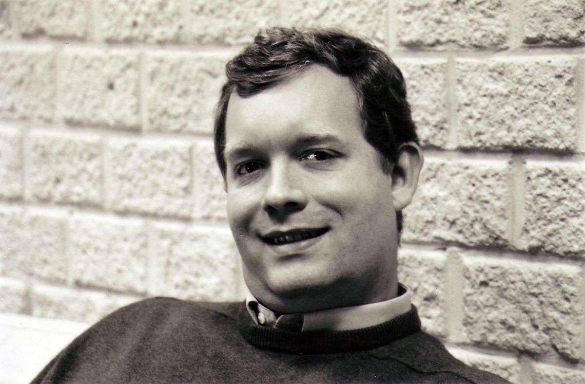 Black-and-white portrait of a young Christophe Lenaerts smiling in front of a brick wall