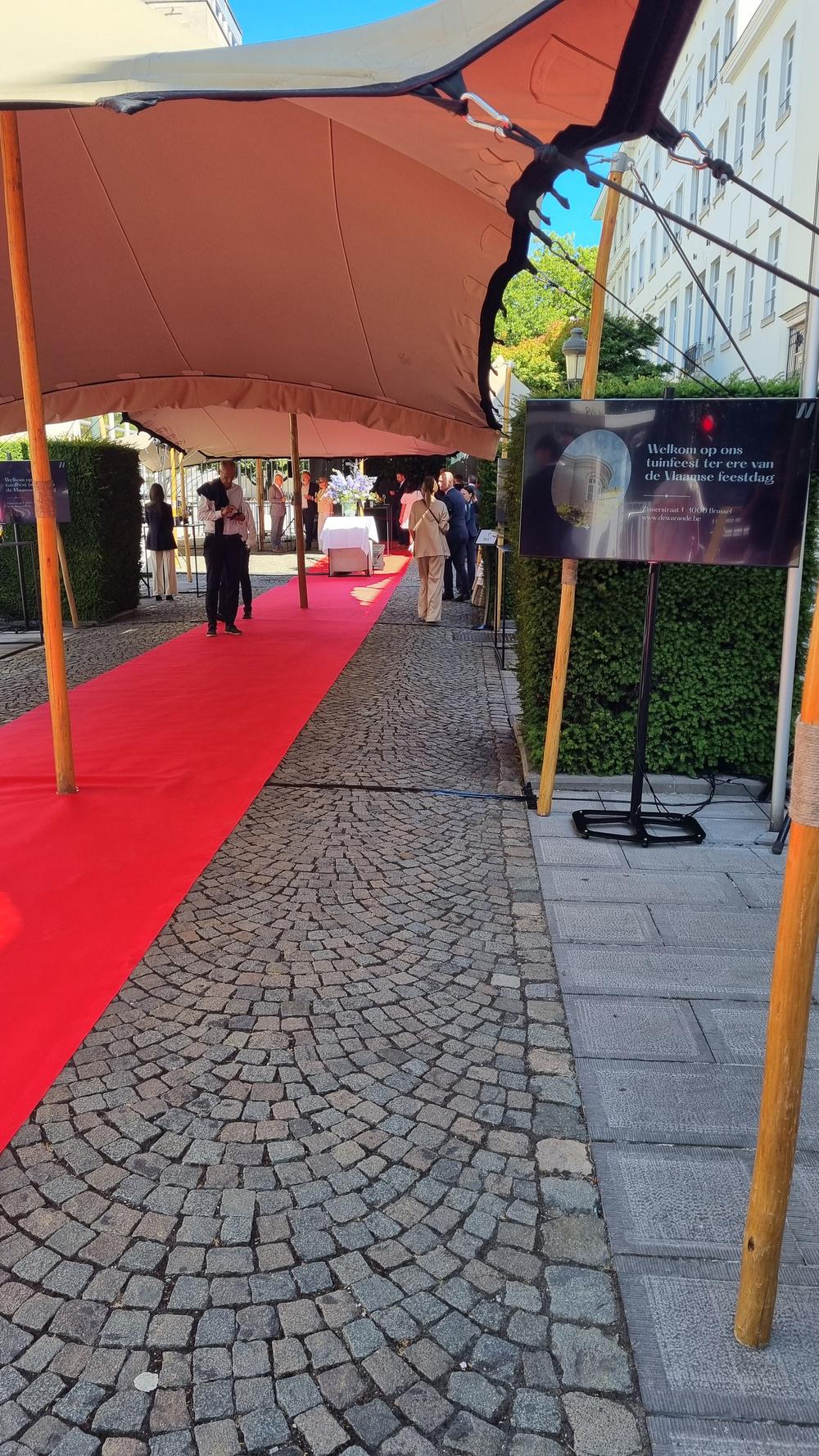 Red carpet on a cobbled path to the De Warande garden party, a screen welcoming guests for the Flemish holiday