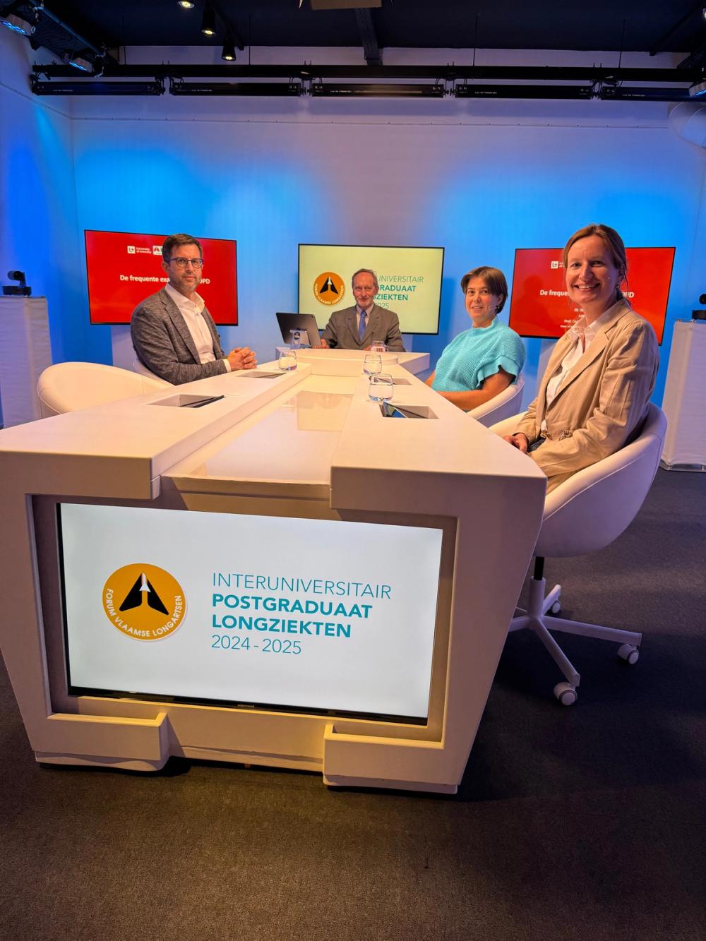Four panellists at a studio desk whose screen reads Interuniversitair Postgraduaat Longziekten 2024-2025