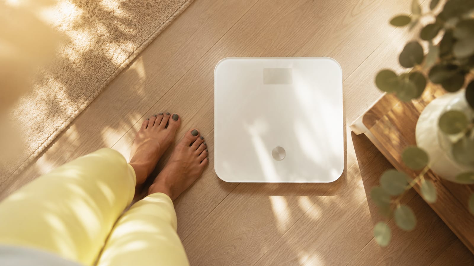 Frau steht barfuß auf einer digitalen Körperwaage — Gewichtsveränderungen gehören zu den häufigen körperlichen Symptomen der Menopause und sind Bestandteil der medizinischen Diagnostik im Menopause Zentrum München.