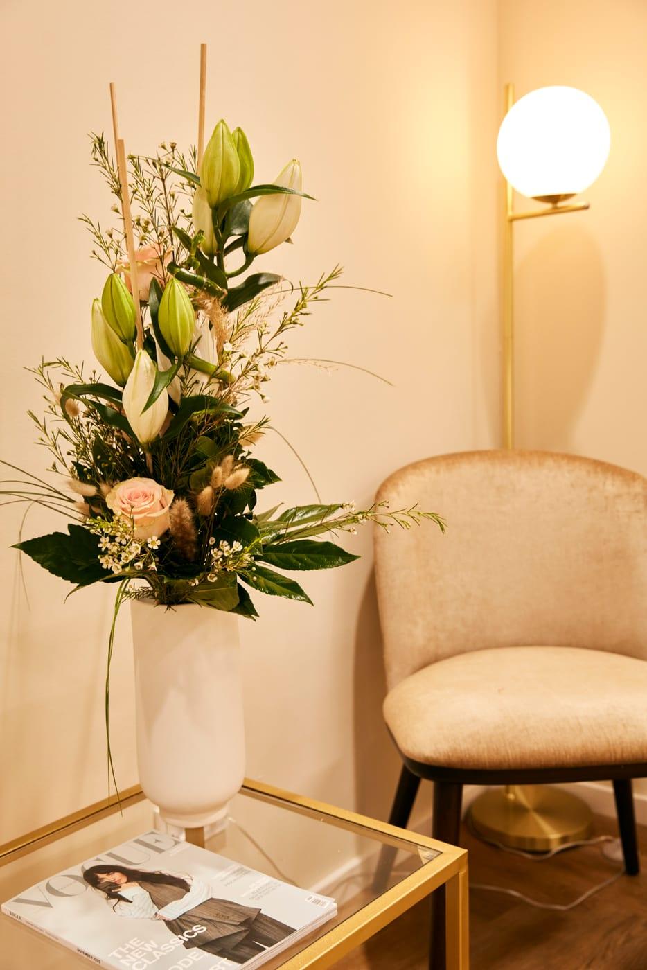 Ruhiger Wartebereich im Menopause Zentrum mit Blumengesteck und Sessel – eine angenehme, diskrete Atmosphäre für die persönliche Beratung.
