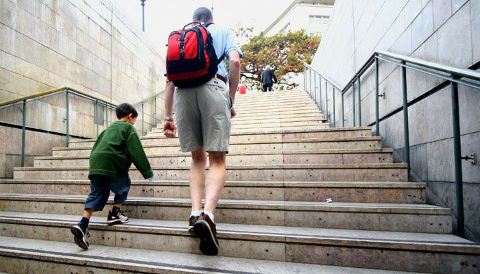 A man and a child going up the stairway to a public plaza.