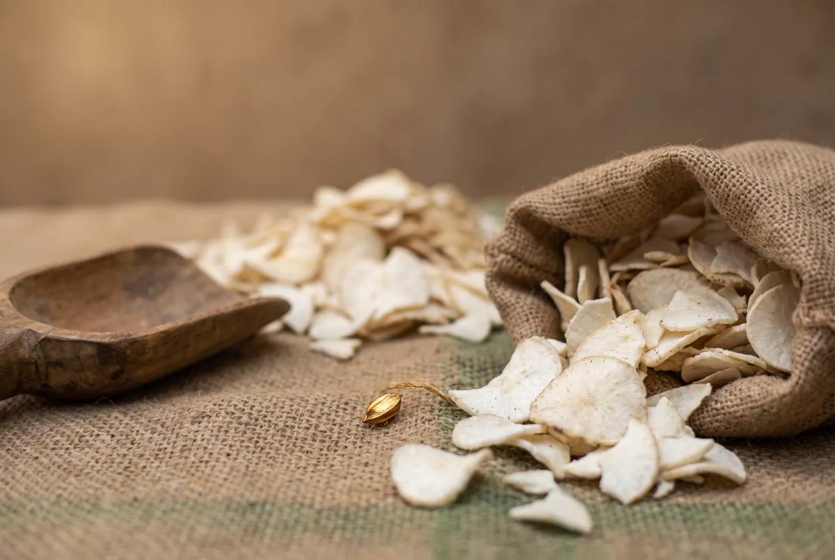 Cassava chips and pellets spilling from an open jute sack onto jute cloth