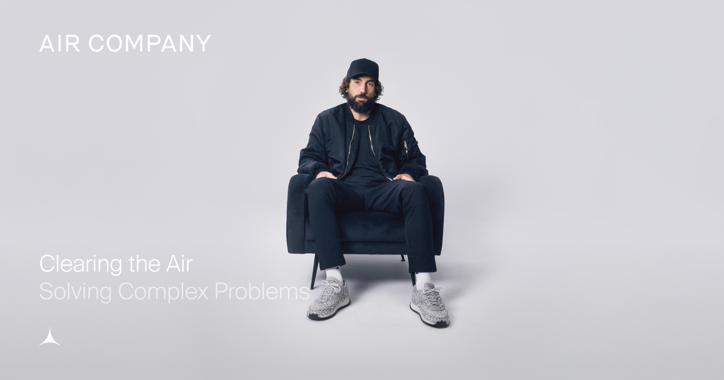 AIRCO (formerly Air Company) co-founder and CEO sitting in a chair on a grey background. hate on and sneakers.