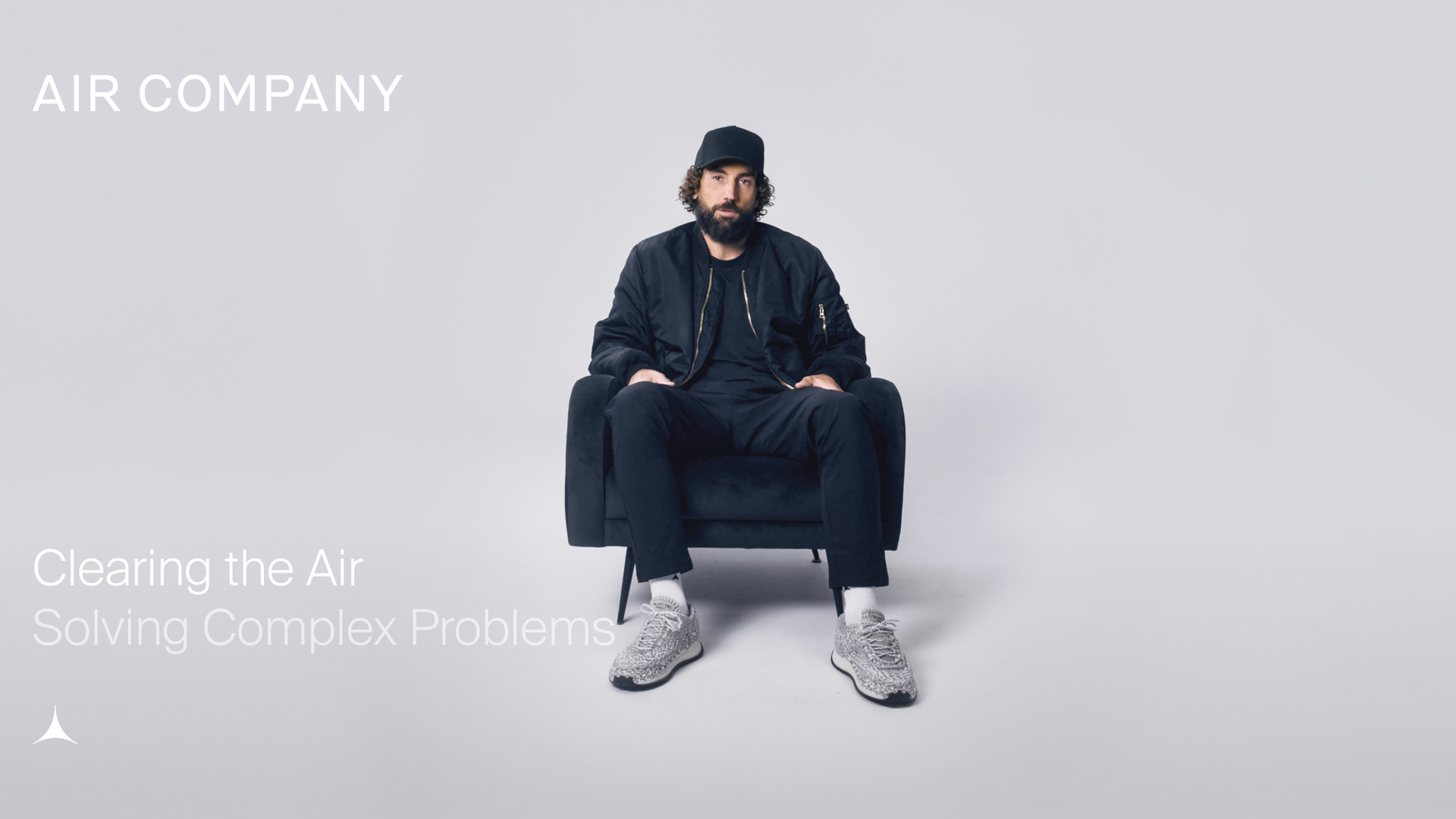 AIRCO (formerly Air Company) co-founder and CEO sitting in a chair on a grey background. hate on and sneakers.