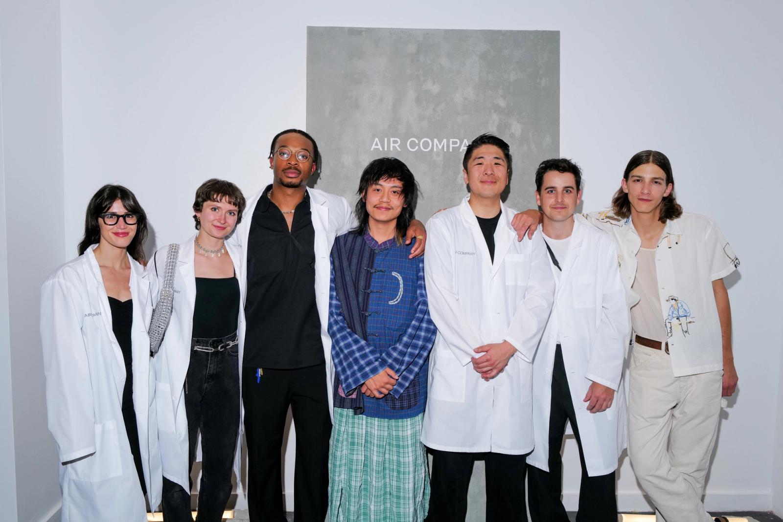 row of seven people smiling and wearing lab coats. aerthship team. 