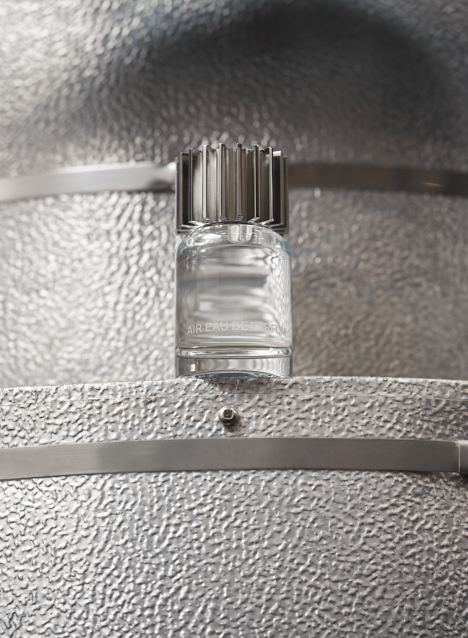 glass fragrance bottle sitting on a silver metal reactor