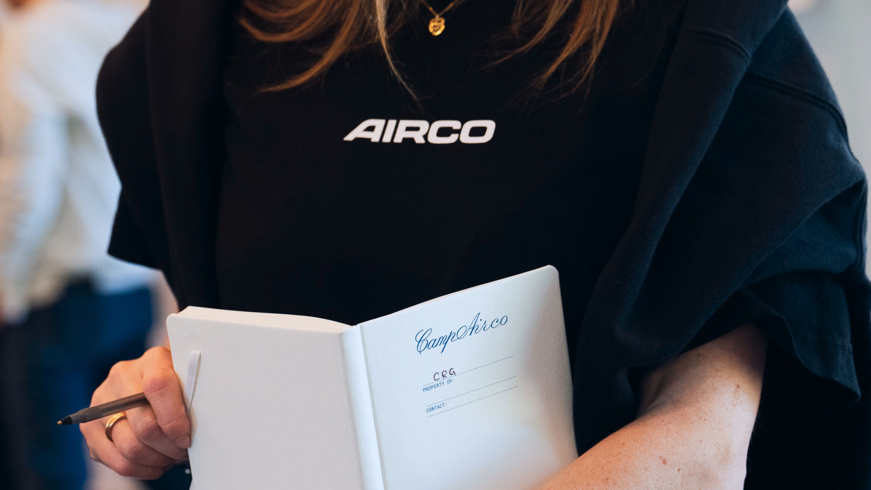 Person wearing Airco hoodie holding notebook