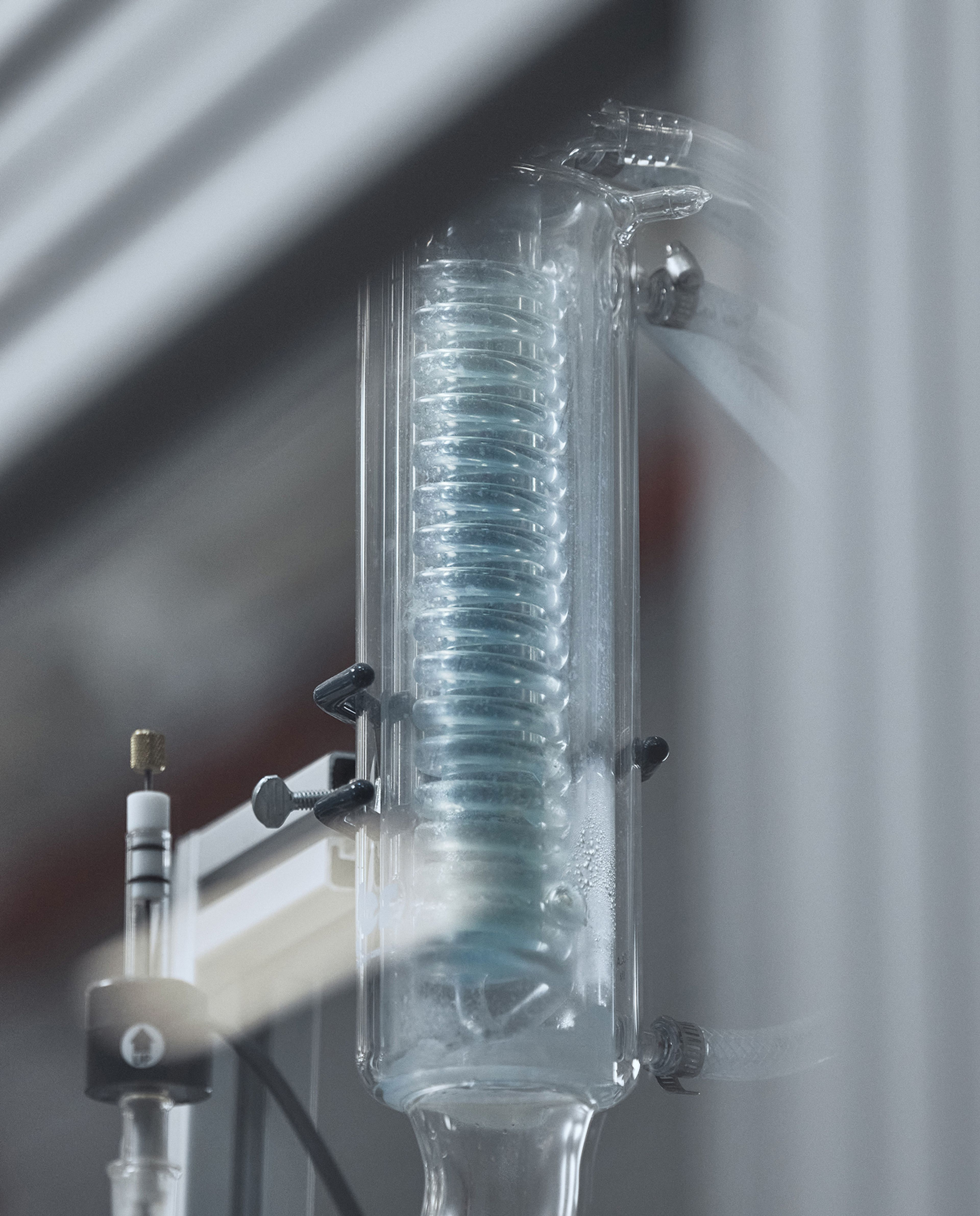 A glass condenser with a spiral coil and condensation inside.